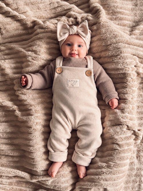 Elastische Cord-Latzhose in Sandbeige für Babys mit Holzknöpfen und Cozy-Club-Patch
