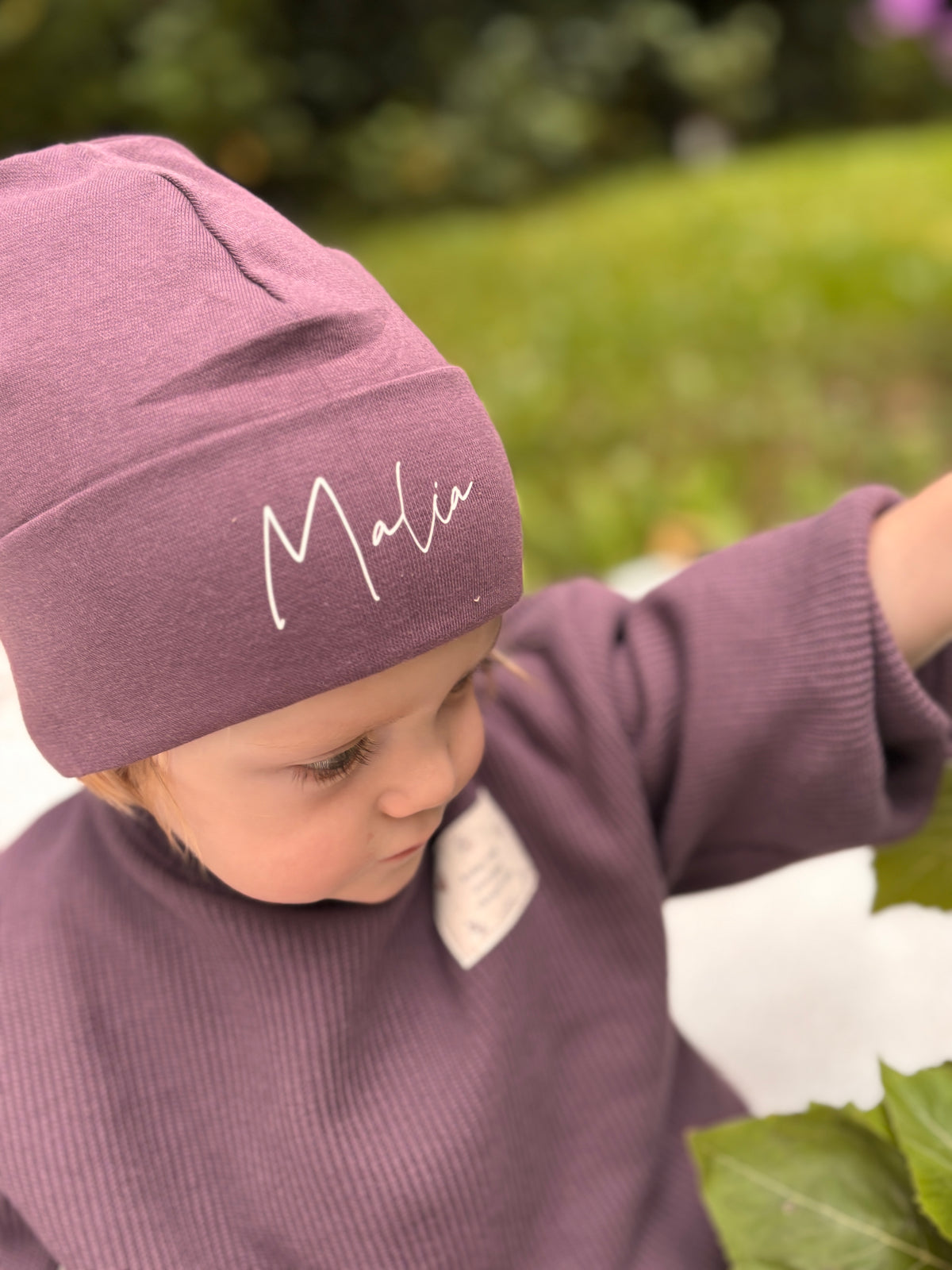Personalisierte Baby- und Kinder-Beanie in Bordeaux mit weißem Wunschnamen und breitem Umschlag

