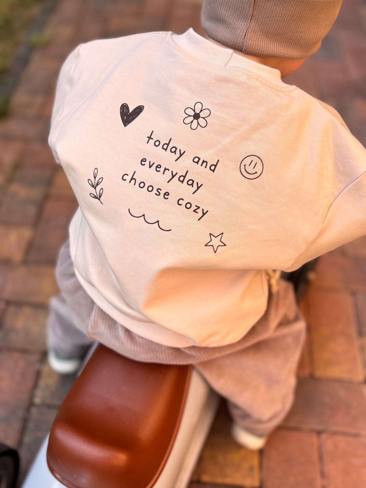 Mitwachsendes Oversize-Sweatshirt in Sandbeige für Babys und Kinder mit kleinem braunem Smiley auf der Vorderseite
