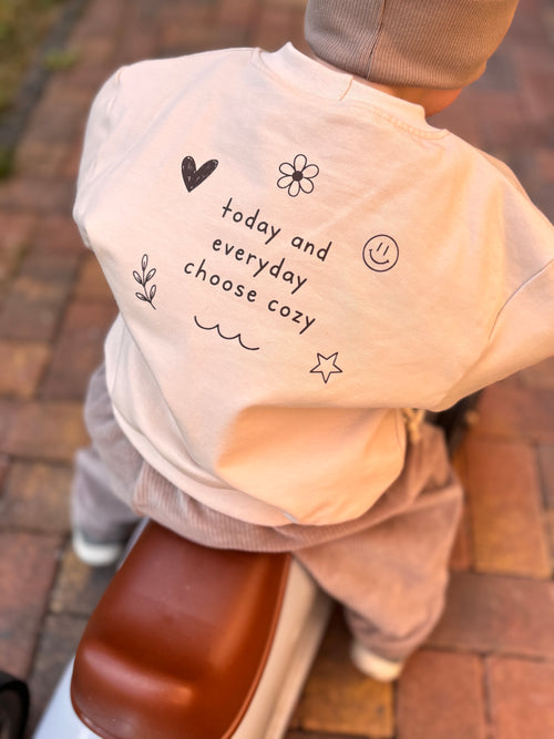 Mitwachsendes Oversize-Sweatshirt in Sandbeige für Babys und Kinder mit kleinem braunem Smiley auf der Vorderseite
