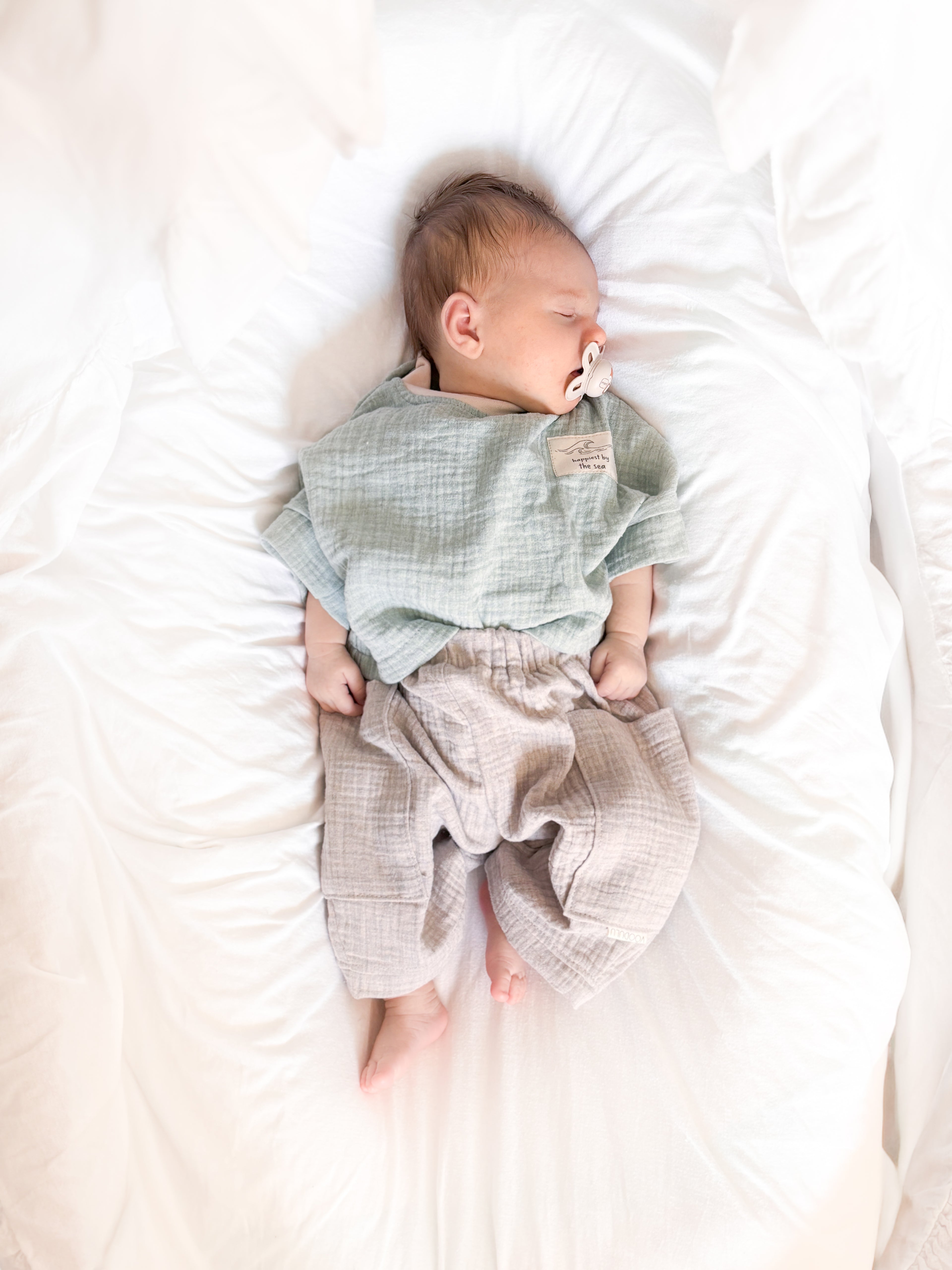 Baby trägt zweiteiliges Musselin Set in Mint und Beige mit Ocean Club Patch aus der VOODULU Sommerkollektion