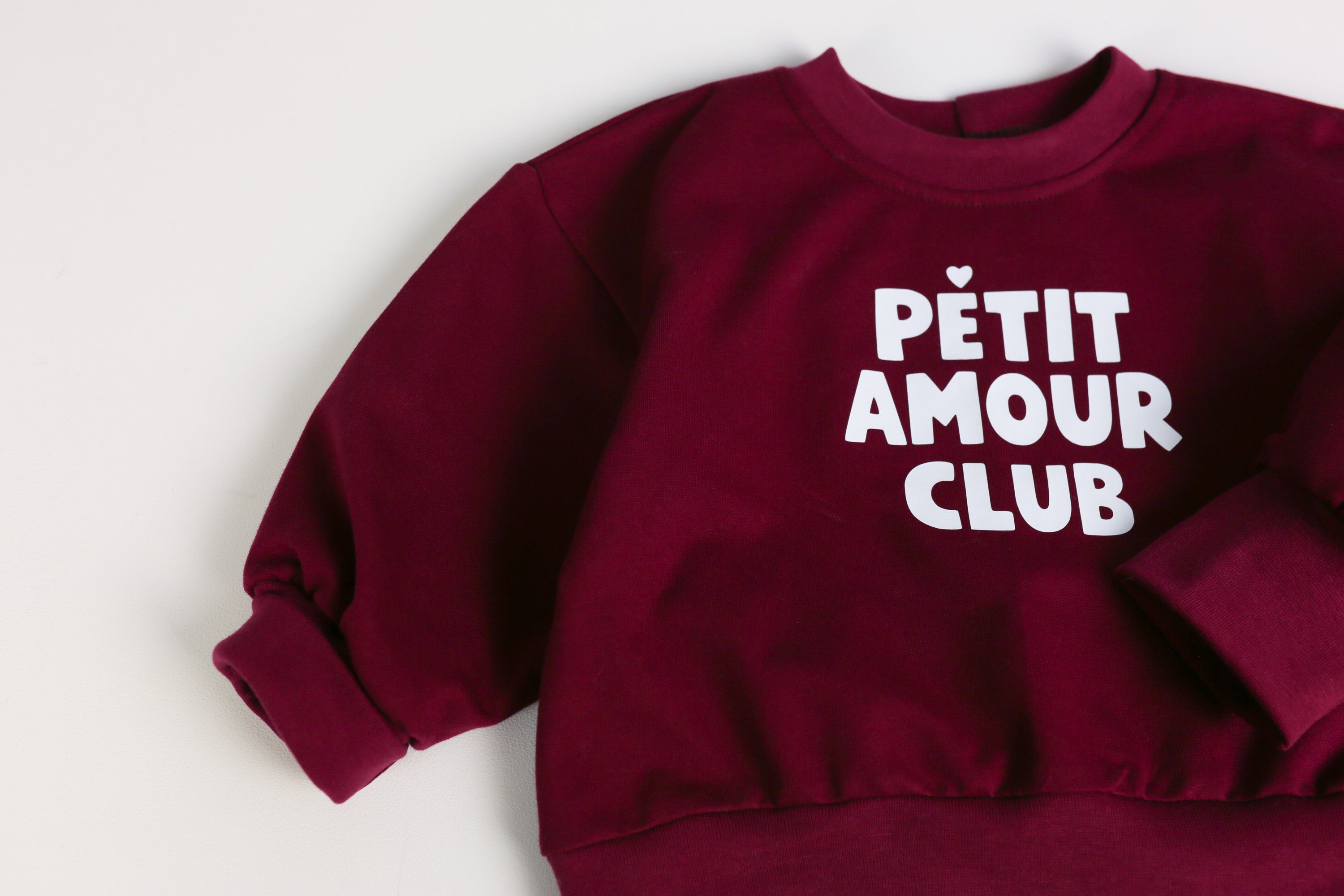 Großes Petite Amour Club Statement auf dunkelrotem Sweatshirt
