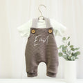 Personalisierte Baby Latzhose in Braun aus weichem Rippenjersey mit gestreiften Trägern und Holzknöpfen. Individuell mit dem Namen Emil bedruckt. Handgefertigte Babyhose für Jungen und Mädchen von VOODULU.