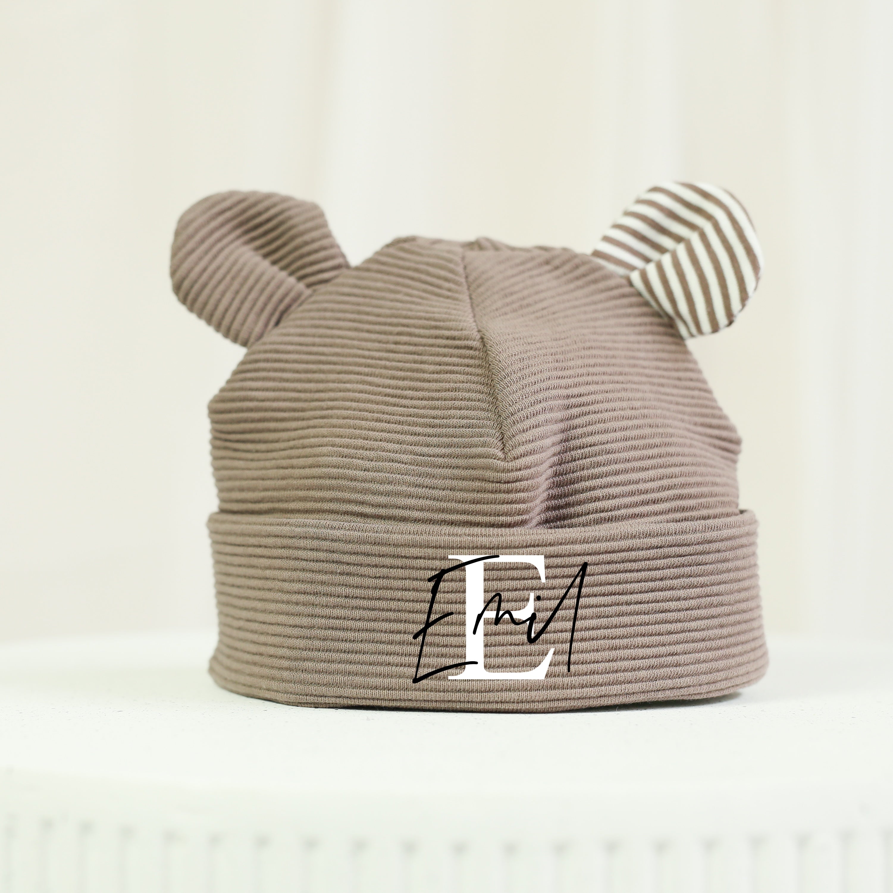 Braune Babymütze mit niedlichen Bärenohren und personalisiertem Namen Emil. Die weiche Mütze aus hochwertigem Rippenjersey ist ein liebevolles Geschenk zur Geburt und begleitet Babys stilvoll durch die ersten Monate..