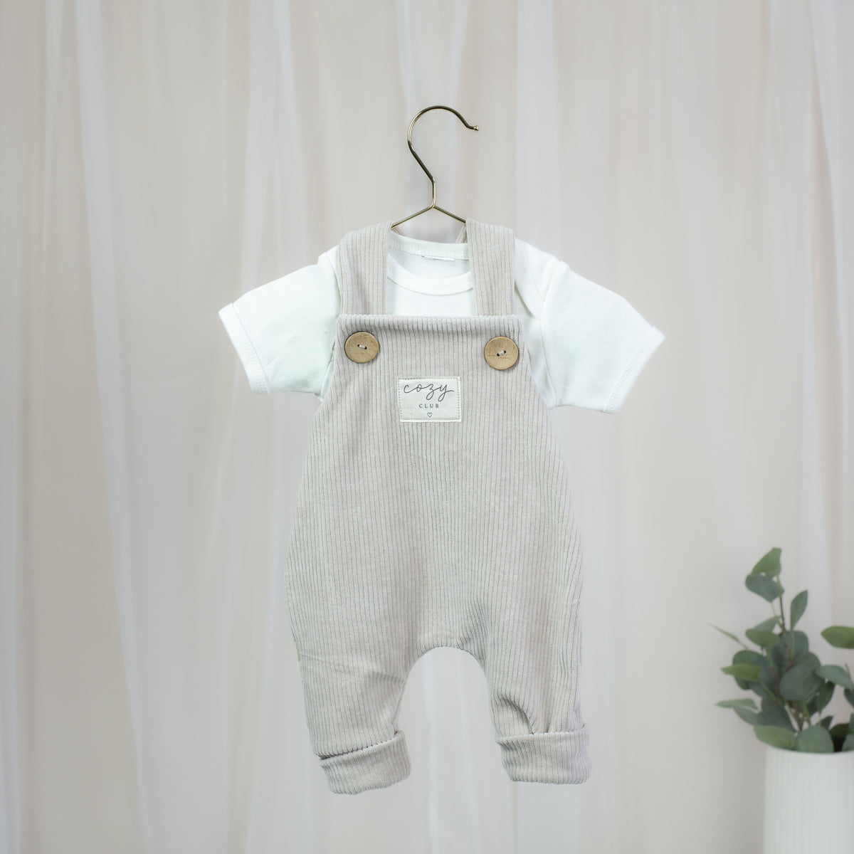 Elastische Cord-Latzhose in Sandbeige für Babys mit Holzknöpfen und Cozy-Club-Patch
