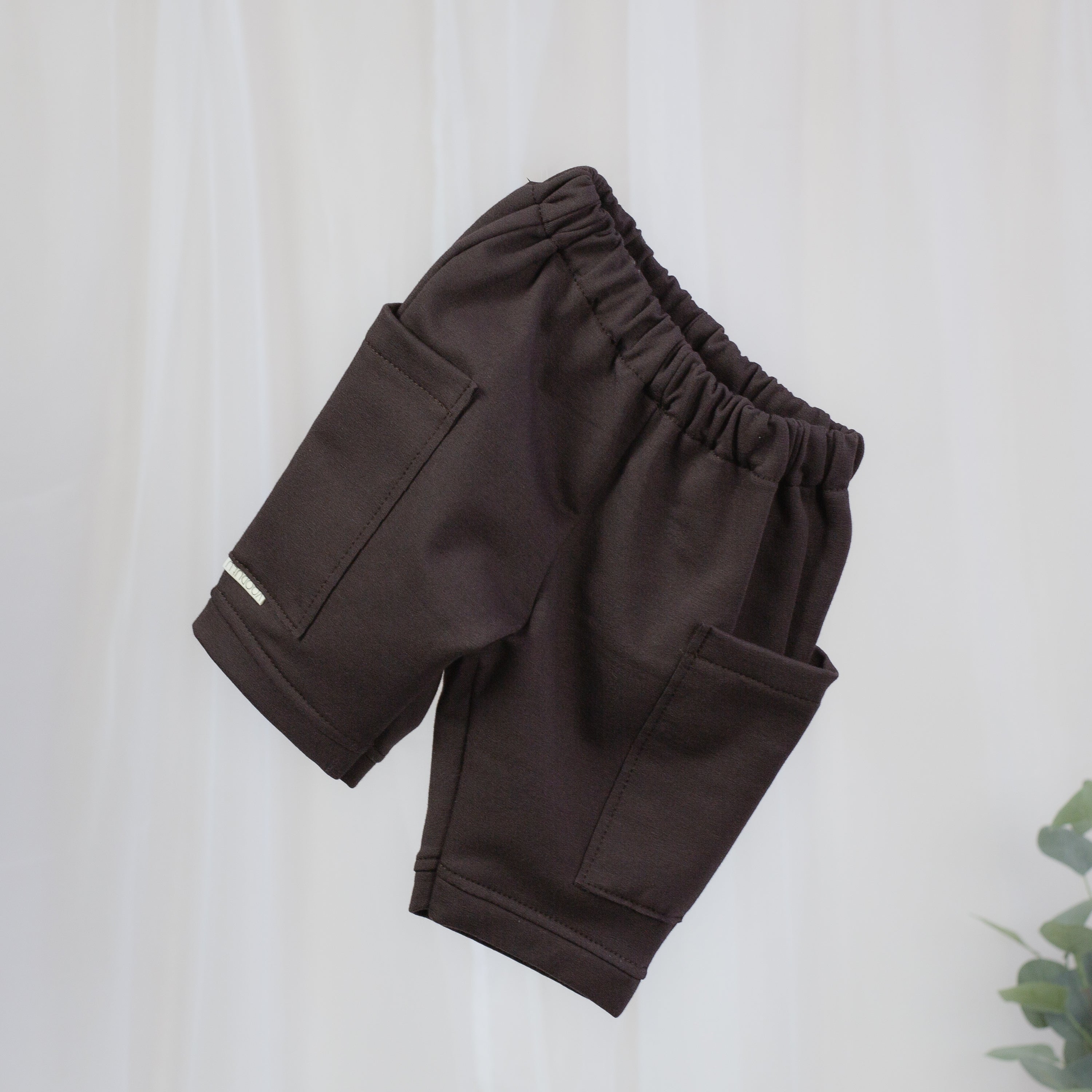 Schokobraune Sweat Barrel Hose für Babys und Kinder mit elastischem Bund und großen aufgesetzten Taschen
